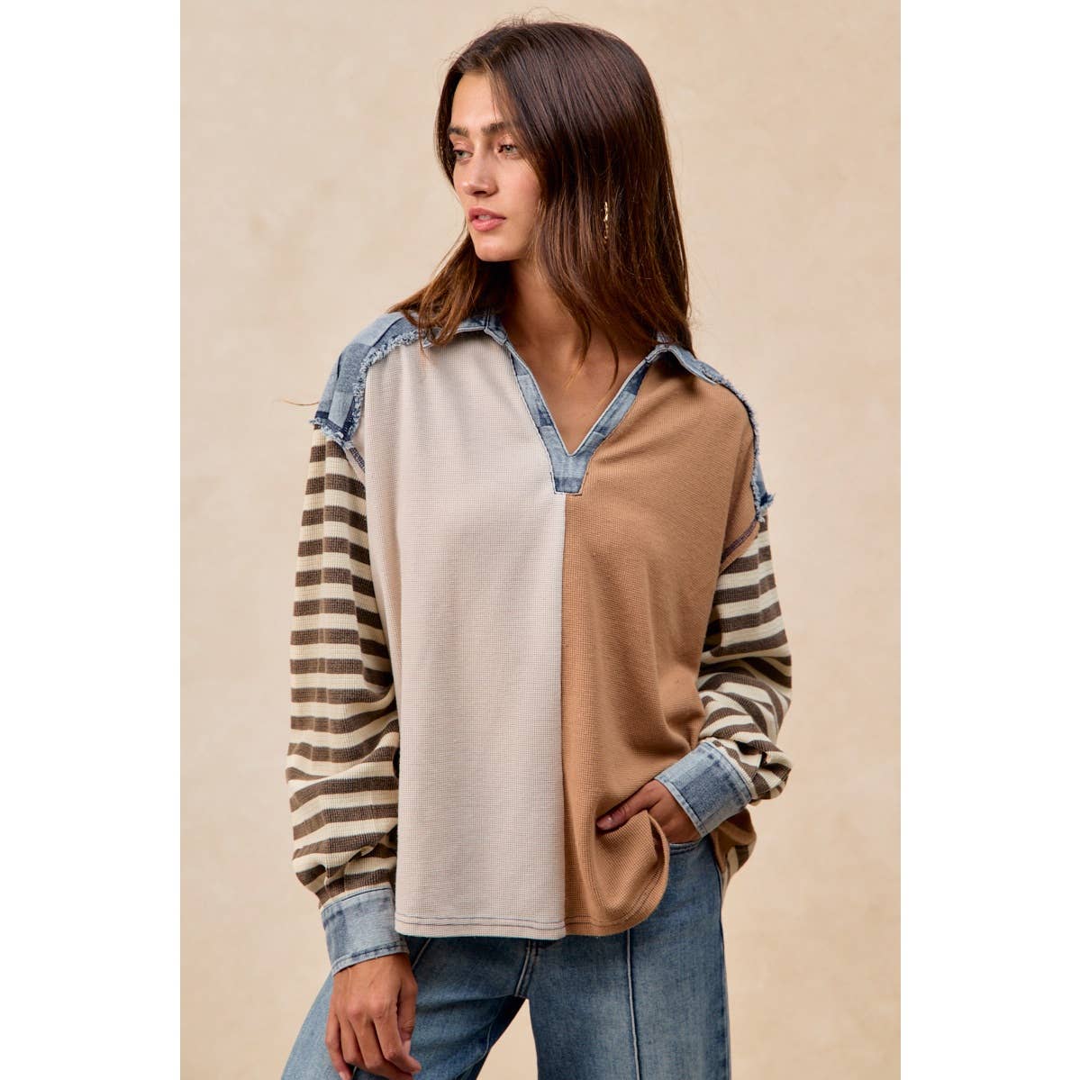 Woman wearing a color-blocked shirt with striped sleeves on a beige background