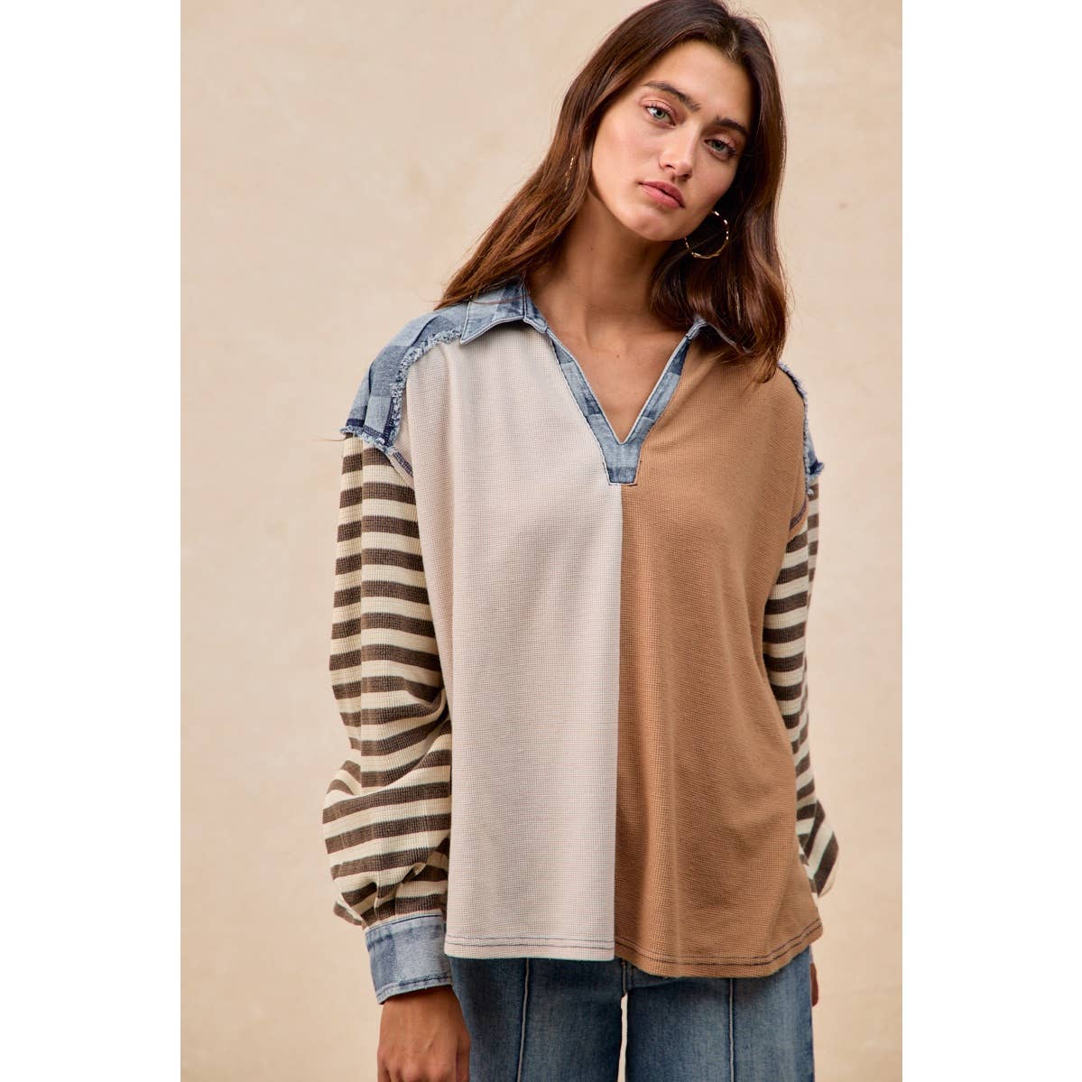 Woman wearing a two-tone shirt with striped sleeves against a beige background