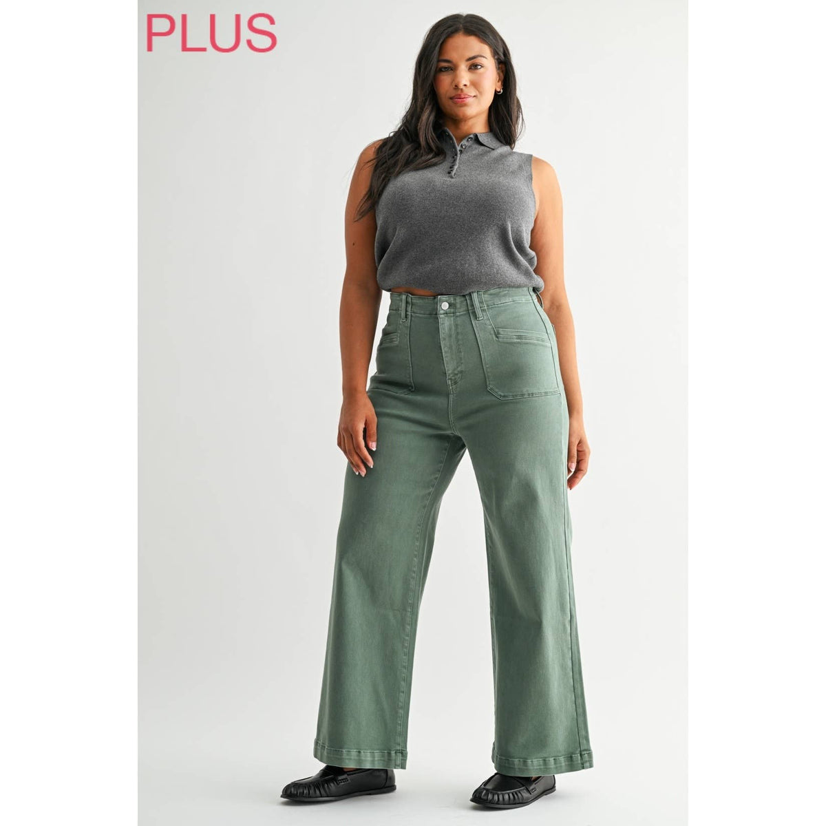 Woman wearing green wide-leg jeans and a gray sleeveless top on a white background