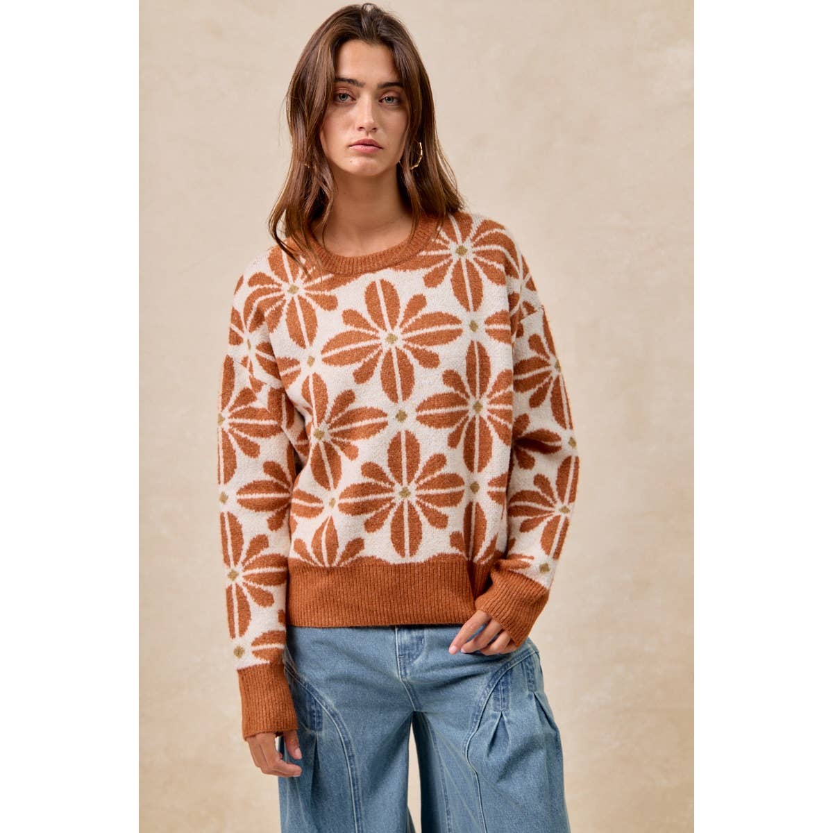 Woman wearing a patterned sweater and jeans against a beige background