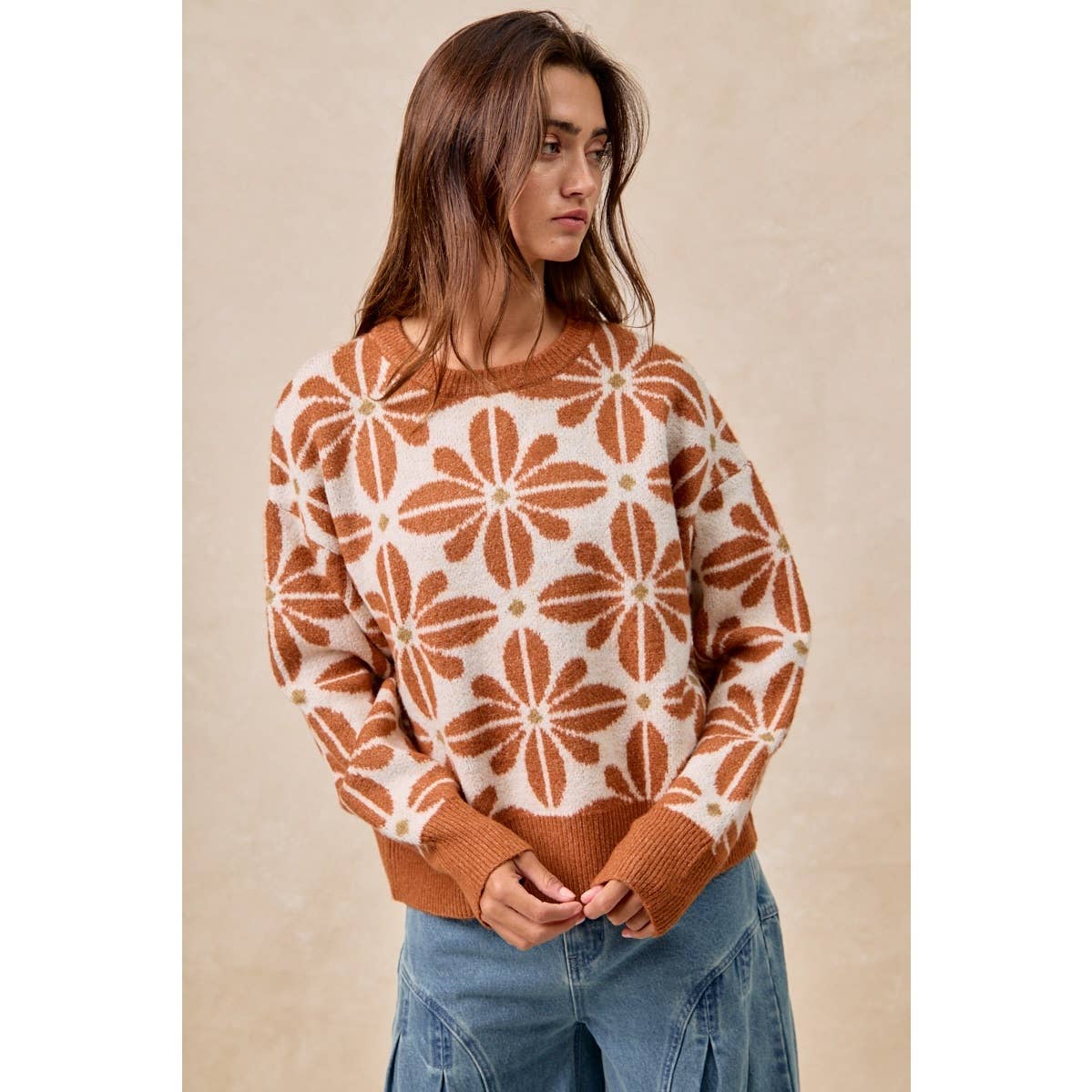 Woman wearing a brown and white patterned sweater against a beige background