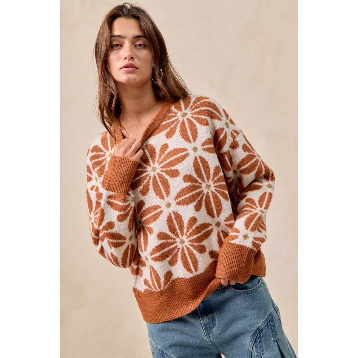 Woman wearing a brown and white patterned sweater against a beige background