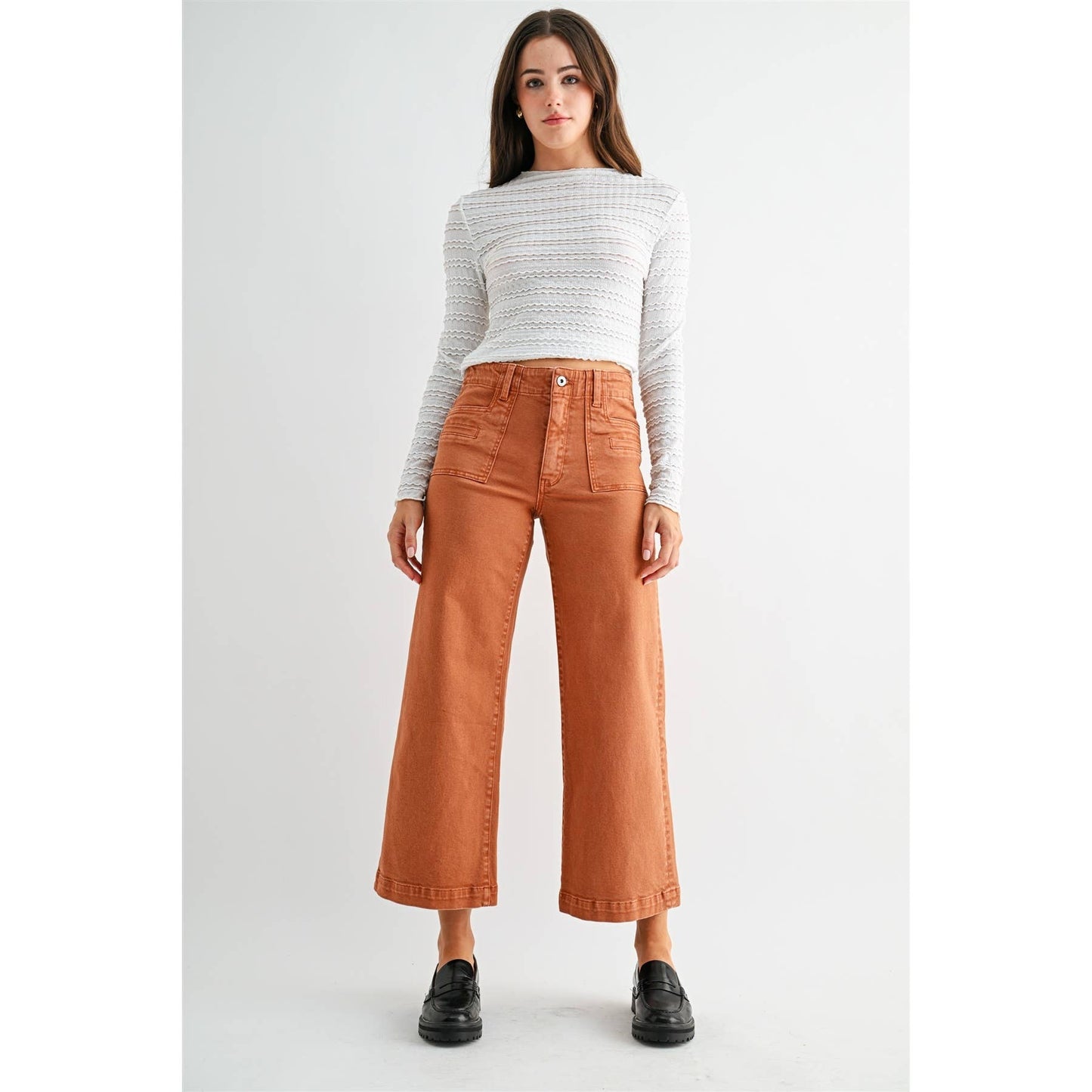 Woman wearing a white sweater and brown pants on a white background